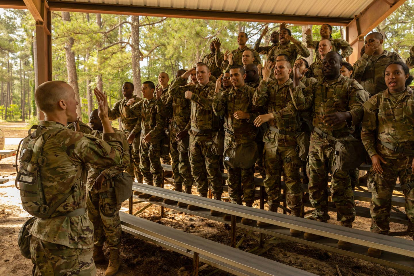 A group of soldiers standing on bleachers and learning how to salute while in basic training.