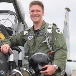 Nolan Peterson wearing pilot uniform in front of aircraft.