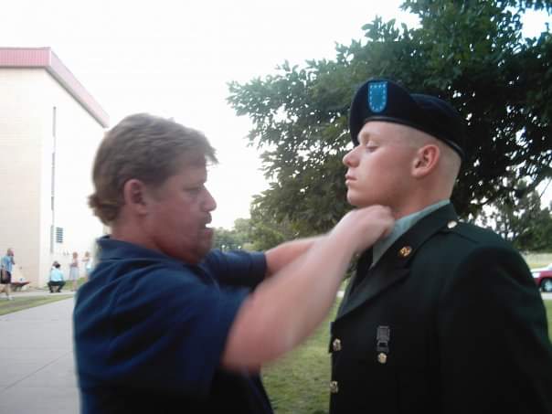 Man fixing tie of Charles Moore in Army uniform.