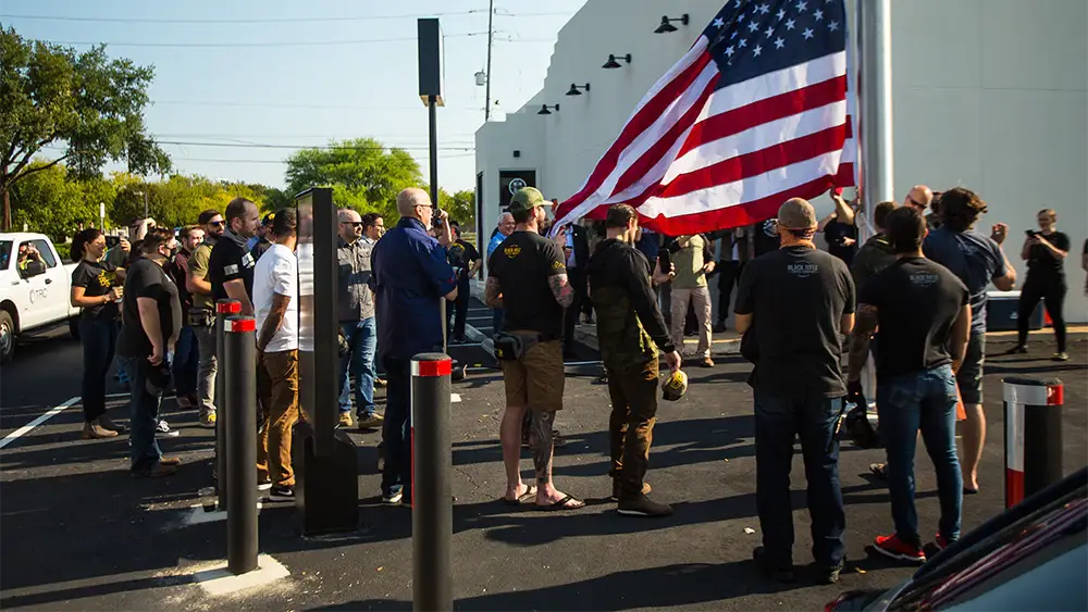 A group of people standing around an American flag.