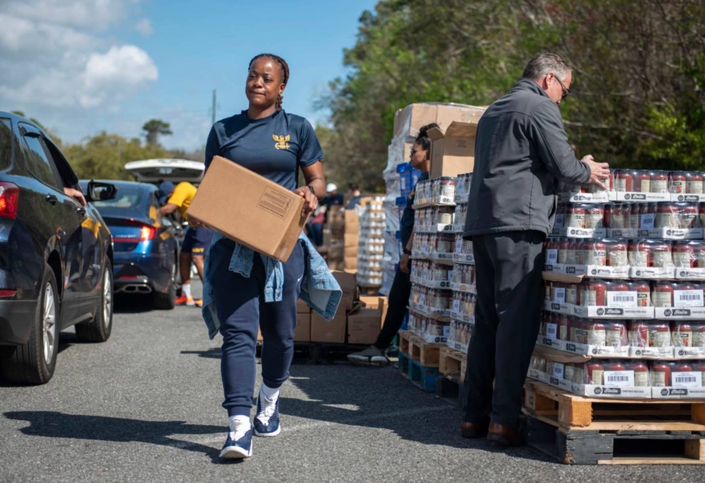 A sailor carries a box of food to a family's car during a food pantry. Food pantries are available in the event of a government shutdown. 