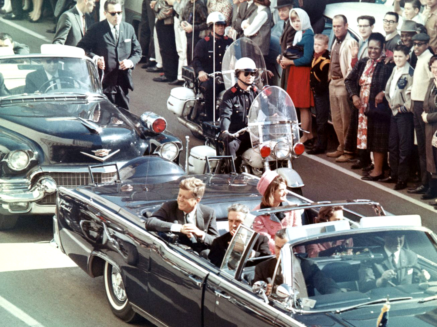 Picture of President Kennedy in the limousine in Dallas, Texas, on Main Street, minutes before the assassination. Also in the presidential limousine are Jackie Kennedy, Texas Governor John Connally, and his wife, Nellie.