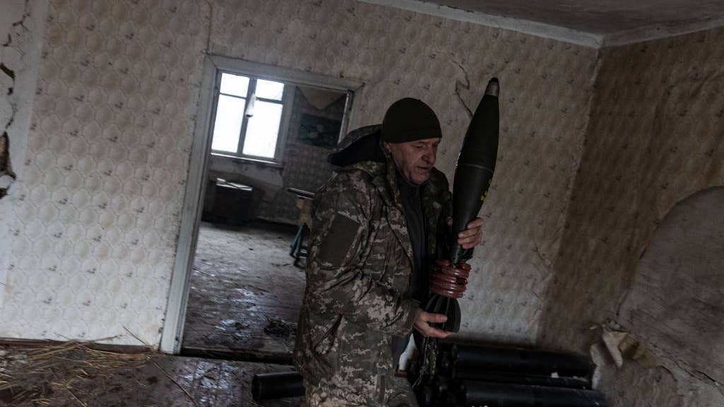 KHARKIV OBLAST, UKRAINE - NOVEMBER 24: Ukrainian soldier of 57 brigade carries a mortar shell at his fighting position in the direction of Kupiansk as Russia-Ukraine war continues in Kharkiv, Ukraine on November 24, 2023. (Photo by Diego Herrera Carcedo/Anadolu via Getty Images)