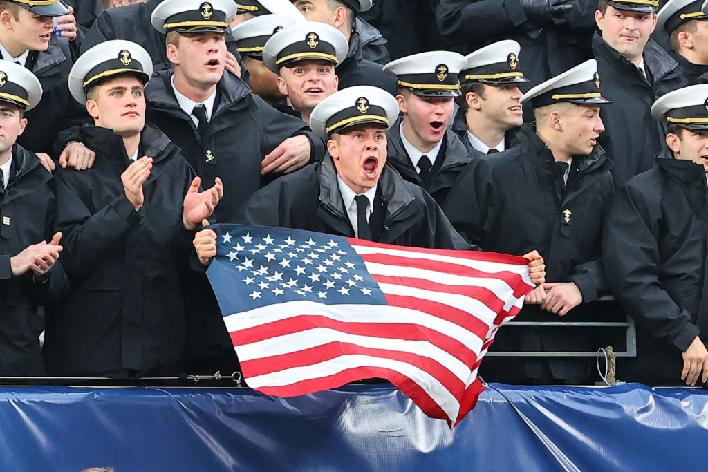 EAST RUTHERFORD, NJ - DECEMBER 11:  Navy Midshipmen in the stands holds an Americn Flag yells during the 122nd Army/Navy college football game between the Army Black Knights and the Navy Midshipmen on December 11, 2021 at MetLife Stadium in East Rutherford, NJ.  (Photo by Rich Graessle/Icon Sportswire via Getty Images)