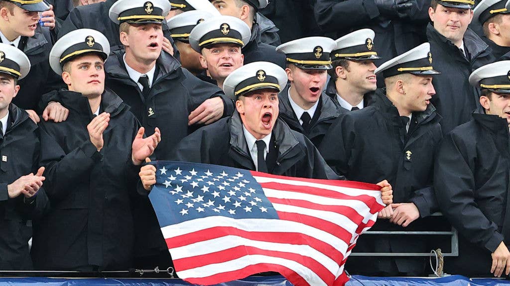 EAST RUTHERFORD, NJ - DECEMBER 11:  Navy Midshipmen in the stands holds an Americn Flag yells during the 122nd Army/Navy college football game between the Army Black Knights and the Navy Midshipmen on December 11, 2021 at MetLife Stadium in East Rutherford, NJ.  (Photo by Rich Graessle/Icon Sportswire via Getty Images)