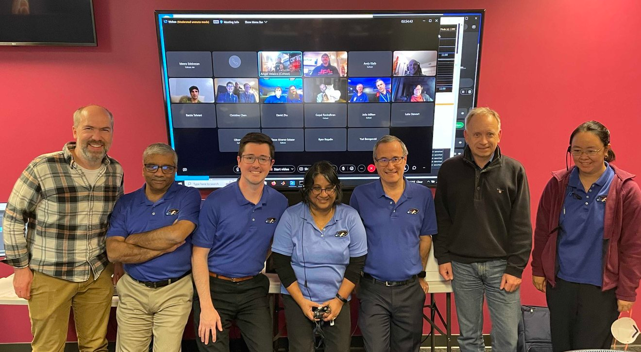 Members of the JPL team pose after the first streamed ultra-HD video was received from deep space. Remote team members (including Taters the cat) appear on the meeting screen. Standing, from left, are: Dan Goods, Abi Biswas, Ryan Rogalin, Meera Srinivasan, Bill Klipstein, Oliver Lay, and Christine Chen.<br>&nbsp;Credit: NASA/JPL-Caltech
