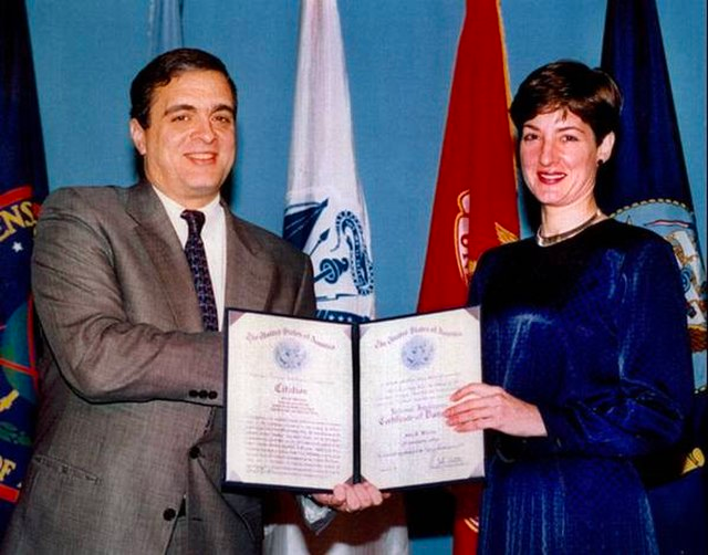 <a href="https://en.wikipedia.org/wiki/Ana_Montes">Ana Montes</a> Montes received a certificate of distinction from <a href="https://commons.wikimedia.org/wiki/George_Tenet">George Tenet</a>, CIA Director, in 1997. Wikimedia Commons.