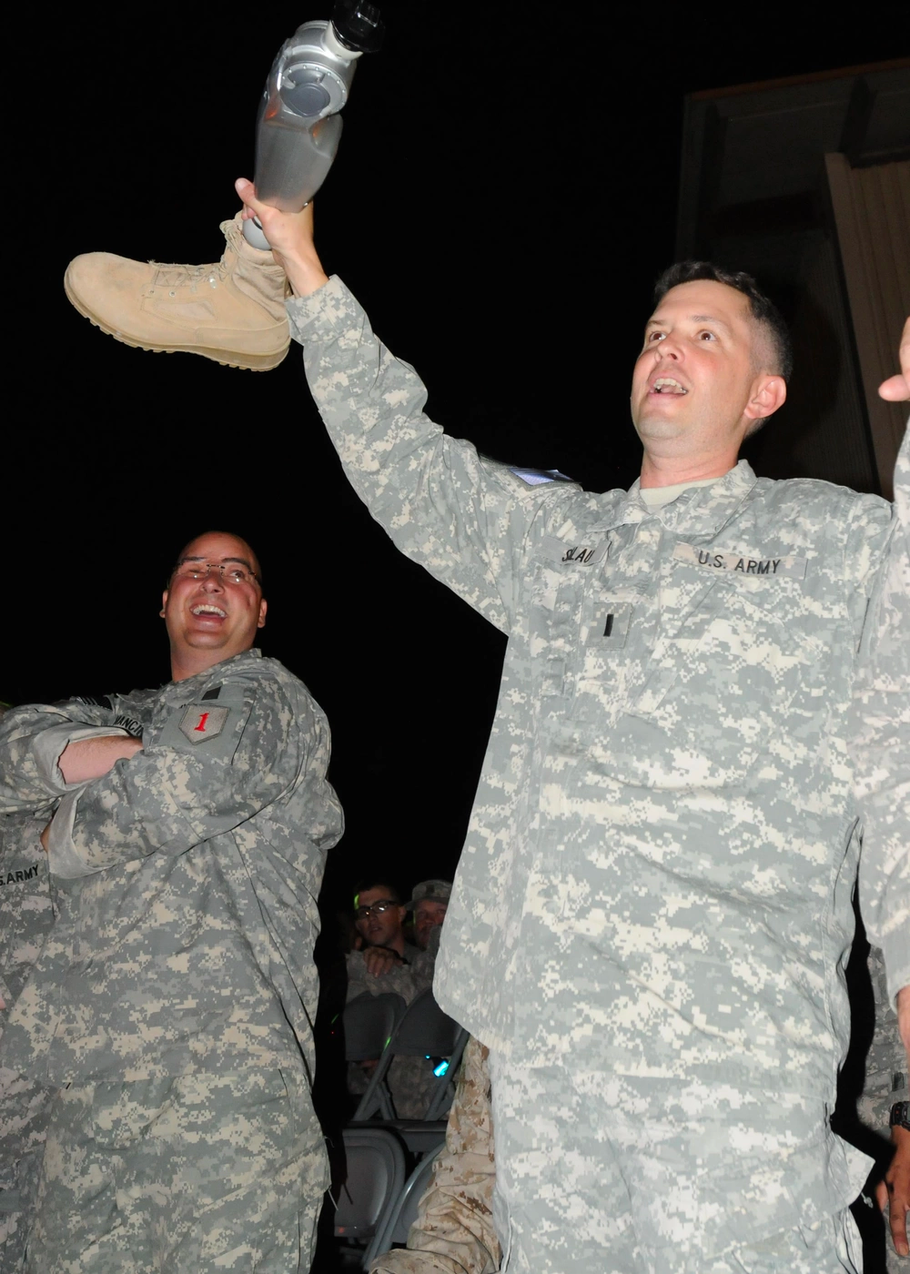 Retired Army 1st Lt. Ed Salau holds his prosthetic leg in the air and sings during a Toby Keith concert on Camp Liberty, April 25, 2011. The warriors participated in Operation Proper Exit IX, which assists wounded troops in getting the closure they need in the healing process. U.S. Army photo.