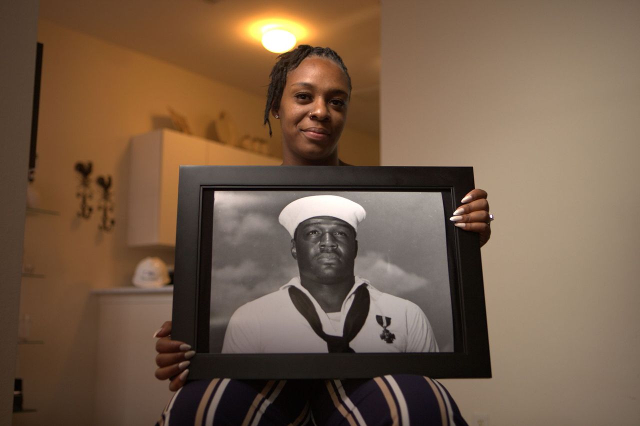 Desare' Allen holds a portrait of her great uncle Doris Miller at Flosetta Miller's home in
Arlington, Texas. "Erased: WW2's Heroes of Color" tells the stories of three Black heroes who miraculously survived the attack on Pearl Harbor. One of these men, mess attendant Doris Miller, defied racial stereotypes when he shot down enemy planes during the attack. (National Geographic/Nelson Adeosun)