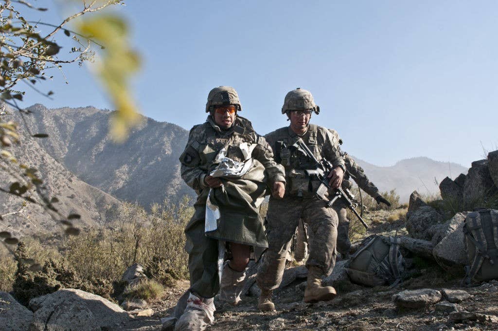A 101st Airborne Division medic escorts a casualty off of a hilltop in the Shal Valley in 2010. Photo: Staff Sgt. Mark Burrell
