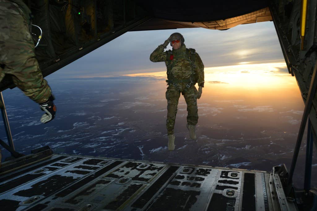A U.S. Soldier assigned to 1st Battalion, 10th Special Forces Group (Airborne) salutes his fellow Soldiers while jumping out of a C-130 Hercules aircraft over a drop zone in Germany, Feb. 24, 2015. (U.S. Army photo by Visual Information Specialist Jason Johnston/Released)