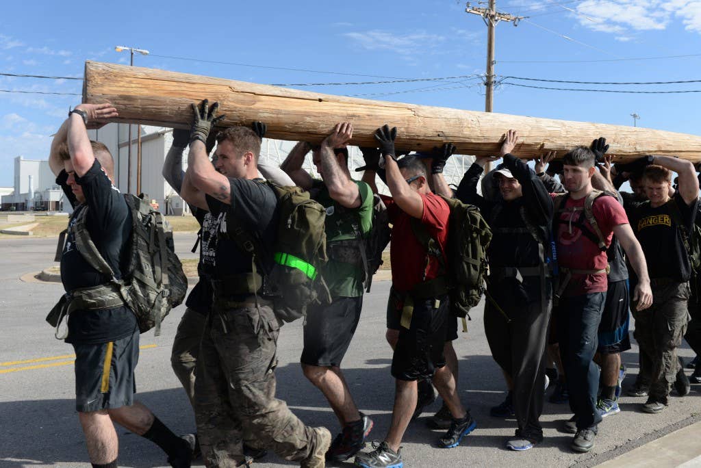 Members of the 97th Air Mobility Wing carry a telephone pole across the base in a GORUCK Light challenge, Oct. 18, 2014. The team carried the pole from the south end of the flight line to the track. The Airmen completed the challenges as a team while carrying weighted rucksacks or backpacks. (U.S. Air Force photo by Airman 1st Class J. Zuriel Lee/Released)