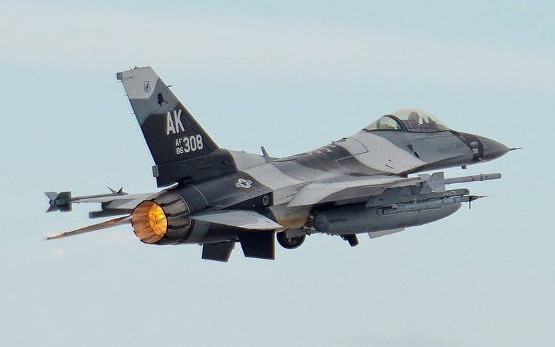 An F-16 launching with external fuel tanks.
