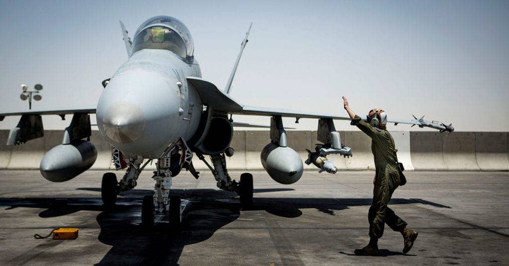 A Marine directs an F/A-18D Hornet returning to an undisclosed location in support of Operation Inherent Resolve, the operation to eliminate the ISIL terrorist group and the threat they pose to Iraq, Syria, and the wider international community, June 9, 2016. (U.S. Marine Corps photo by Sgt. Donald Holbert)