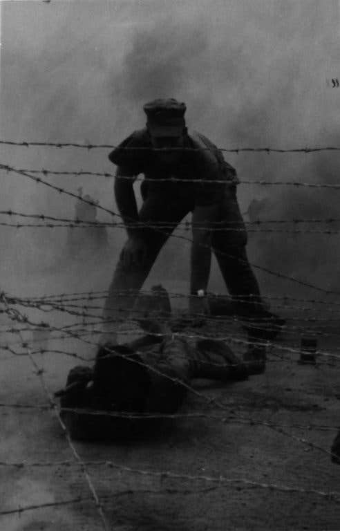 A Vietnamese Popular Force trainee is aided through a barbed wire entanglement on the infiltration course at Mobile Training Team-1 located just outside Tam Ky on July 28, 1968, by Sgt. William C. Gandy. (Photo: U.S. Marine Corps 1st Lt. Joe Collins)