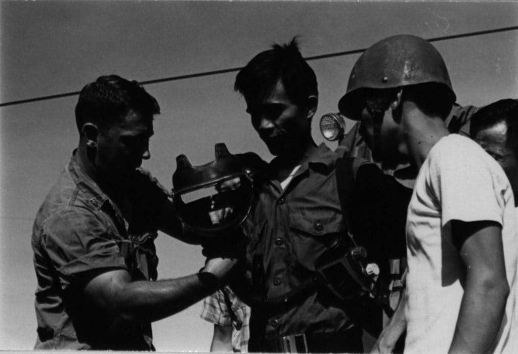 Marine Sgt. Lawrence J. Marchlewski instructs Vietnamese fire fighters in the proper use of their gas mask. The device allows firemen to combat flames in heavy smoke. (Photo: U.S. Marine Corps Sgt. G.W. Heikkinen)