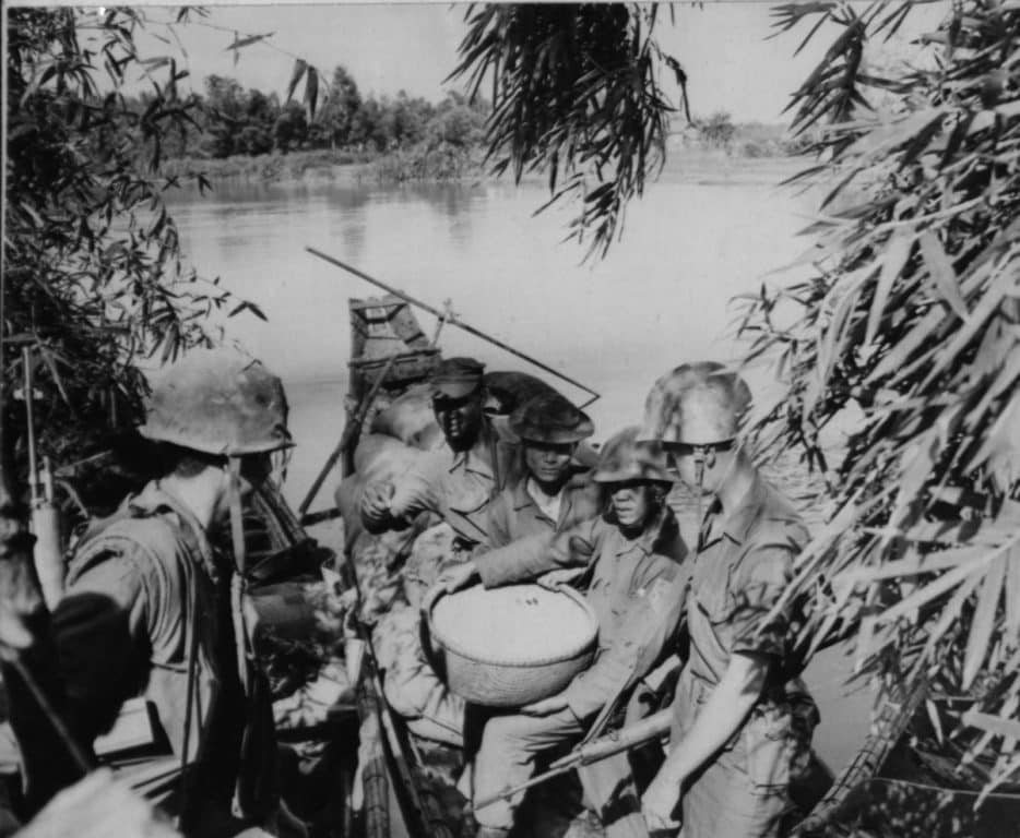 American Marines assist two Vietnamese Popular Force soldiers unloading rice from a small sampan. The rice was confiscated from a Viet Cong cache in the walls of a hut in Phu Bai village on Oct. 23, 1966. (Photo: U.S. Marine Corps Staff Sgt. Highland)