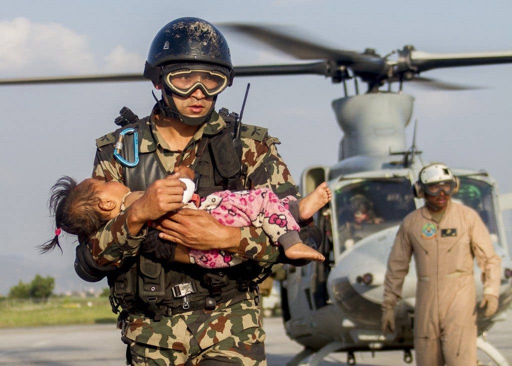 A Nepalese soldier carries a young earthquake victim from a U.S Marine Corps UH-1Y Venom helicopter assigned to Joint Task Force 505 to a medical triage area at Tribhuvan International Airport, Kathmandu, Nepal, after a 7.3 magnitude earthquake struck the country, May 12, 2015. (Photo: U.S. Marine Corps Gunnery Sgt. Ricardo Morales)