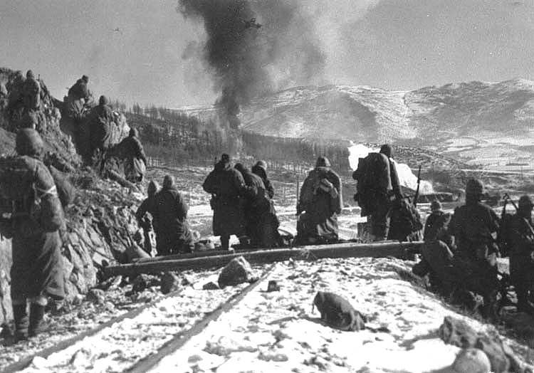 Marines at Hagaru perimeter watch Corsairs drop napalm on Chinese as Item Company 31/7 moves around high ground at left to attack enemy position. (Photo: US Marine Corps)