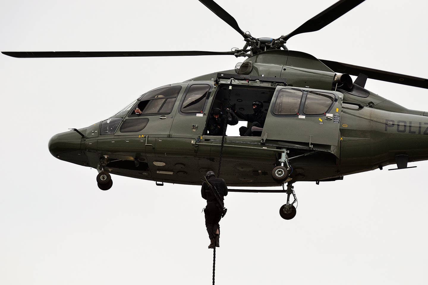 An SEK operative fast-ropes from a police helicopter during a demonstration (Photo Wikimedia Commons)