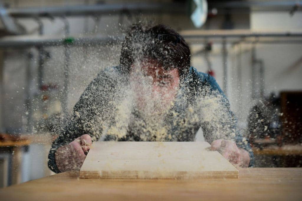Stefano De Bortoli, 31st Force Support Squadron wood hobby shop manager, blows sawdust off a piece of wood, March 24, 2015, at Aviano Air Base, Italy.