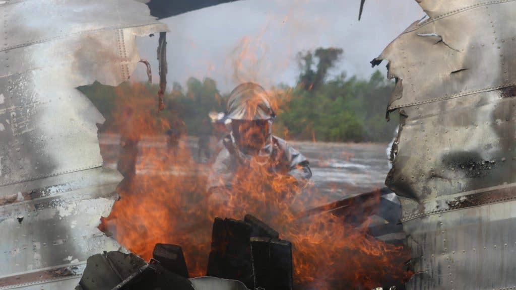 Cpl. Justin Groom stokes the fire inside of a scrap airplane during a fire response scenario at Utapao Royal Thai Navy Airfield, Kingdom of Thailand. (Marine Corps photo by Cpl. Joshua Murray)
