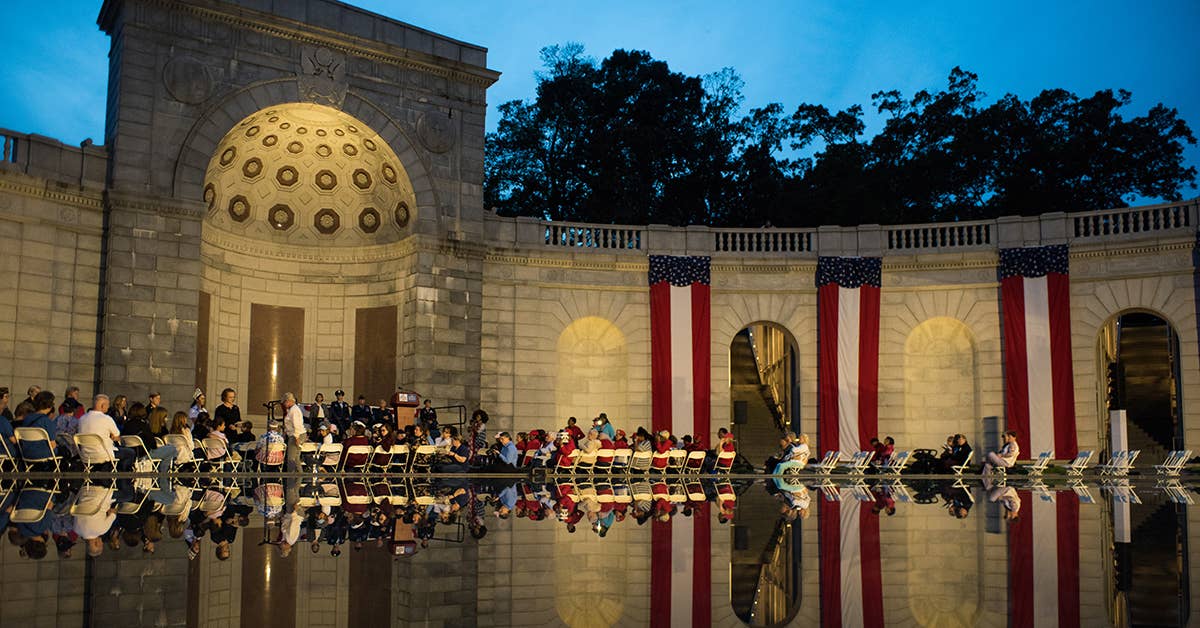 Women toss rose petals into the reflecting pool of the Women in Military Service for America memorial during a ceremony that honored the 15 fallen women of the US Armed Forces since 2012, Oct. 21, 2017, in Washington DC. US Air National Guard photo by Staff Sgt. Kasey Phipps.
