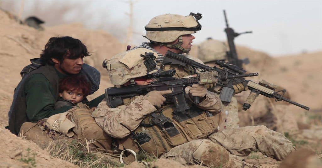 Two U.S. Marines guard two local nationals during enemy contact.