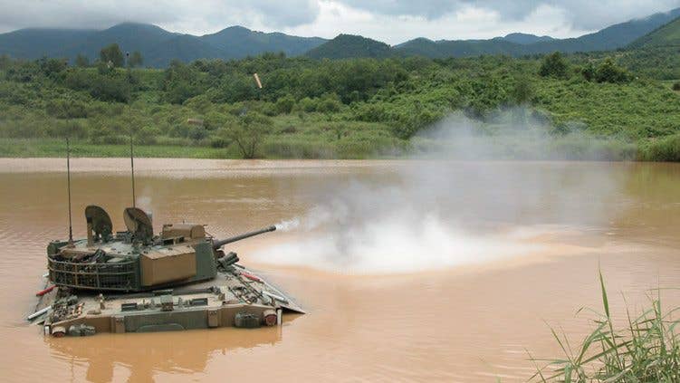 A K21 IFV fires its 40mm gun while crossing a river. (PHoto from Hanwha Defense Systems)