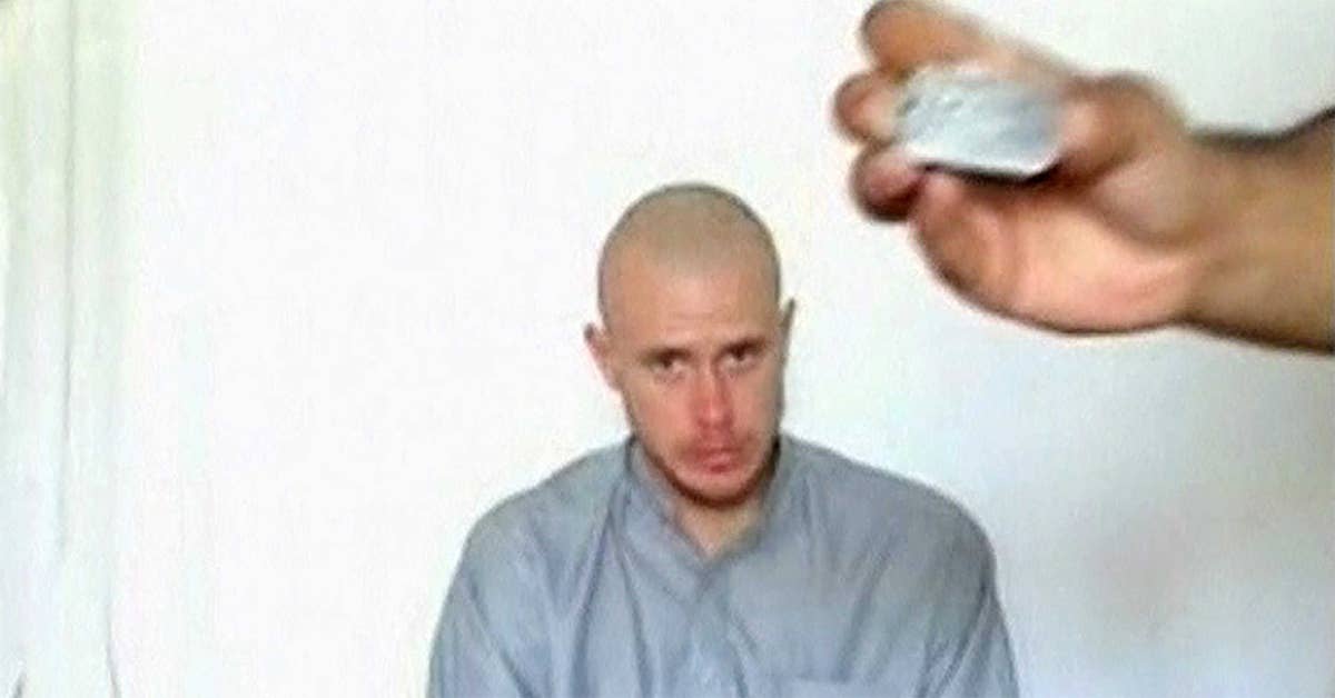Bowe Bergdahl watches as one of his captors displays his identity tag in this still from a Taliban-released video.