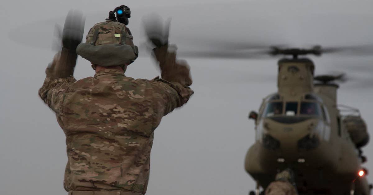 A US Army Soldier, assigned to 2nd Brigade Combat Team, 101st Airborne Division, guides a pilot into place during sling load operations, Aug. 11, 2016 at Camp Buehring, Kuwait. Sling load operations allow US Army Central to move artillery and trucks and shipping containers for mobile operations in the Middle East. Army photo by Sgt. Brandon Hubbard