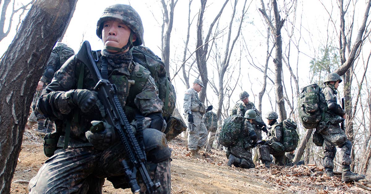 Cadet Huh Choong-bum (left), a third-year cadet at the Korea Military Academy, pulls a guard around his fellow soldiers as they examine the map during the land navigation training at Camp Casey, South Korea, March 27. Photo from DOD.