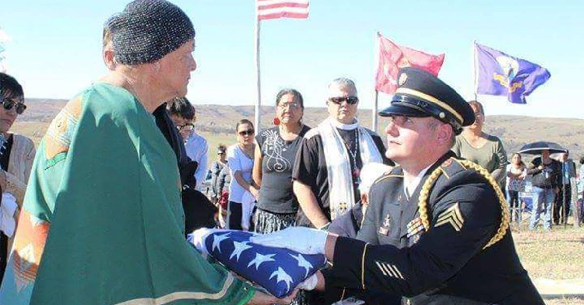 A member of the Honor Guard presents a folded American flag to Eva Iyotte, the lone surviving sibling of Sgt. Philip Iyotte. Photo courtesy of South Dakota Department of Tribal Relations.