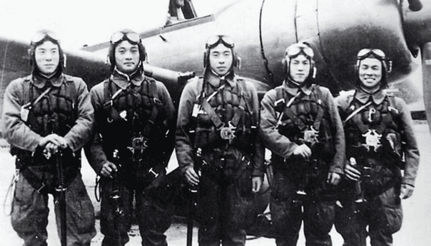 Kamikaze pilots pose together in front of a zero fighter plane before taking off from the Imperial Army airstrip.