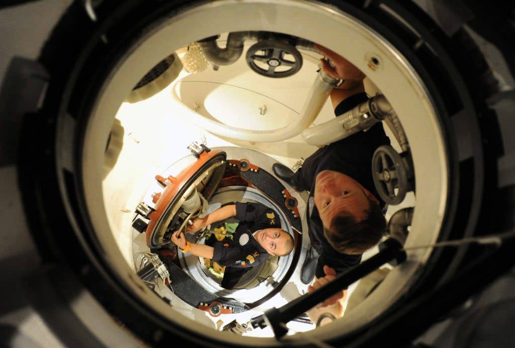 Personnel assigned to the Portuguese navy submarine SKS Tridente climb down to their submarine after mating with the U.S. Submarine Rescue Diving and Recompression System's Pressurized Rescue Module, Falcon, during the NATO exercise Bold Monarch 2011. Bold Monarch is the world's largest submarine rescue exercise with participants and observers from more than 25 countries. The 12-day exercise supports interoperability between submarine rescue units. (Image DVIDS)
