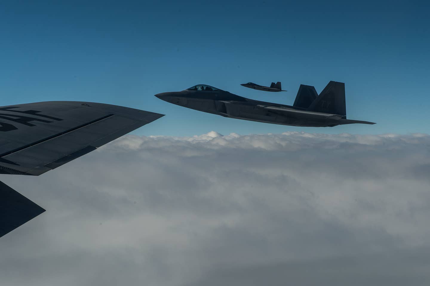 A F-22 Raptors from Tyndall Air Force Base, Fla., fly off the wing of a KC-135 Stratotanker on their way to Iraq, Jan. 30 2015. The F-22s are supporting the U.S. lead coalition against Da'esh. (U.S. Air Force Photo by Staff Sgt. Perry Aston/Released)