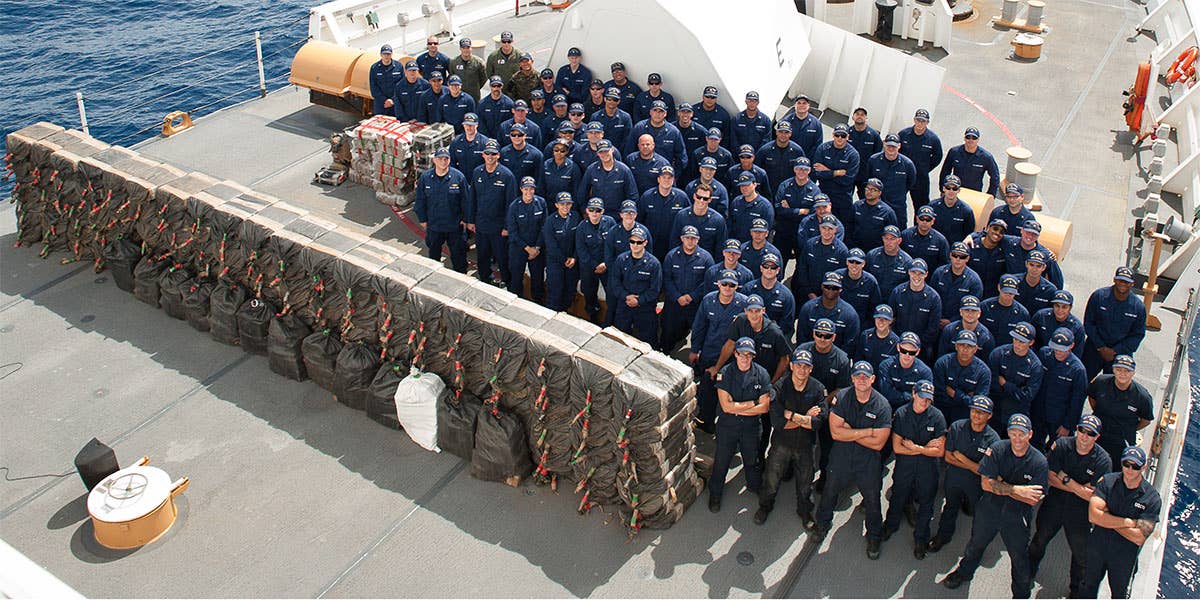 The Coast Guard Cutter Stratton crew is shown with cocaine bales seized from a self-propelled semi-submersible interdicted in international waters off the coast of Central America, July 19, 2015. The Coast Guard recovered more than 6 tons of cocaine from the 40-foot vessel. (Coast Guard photo courtesy of Petty Officer 2nd Class LaNola Stone)