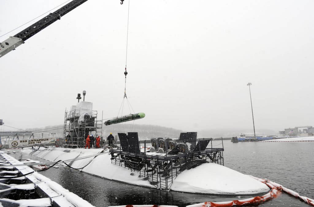 A MK 48 ADCAP torpedo is unloaded from the fast-attack submarine USS Annapolis by Sailors from the Submarine Base New London weapons department during a snowstorm.