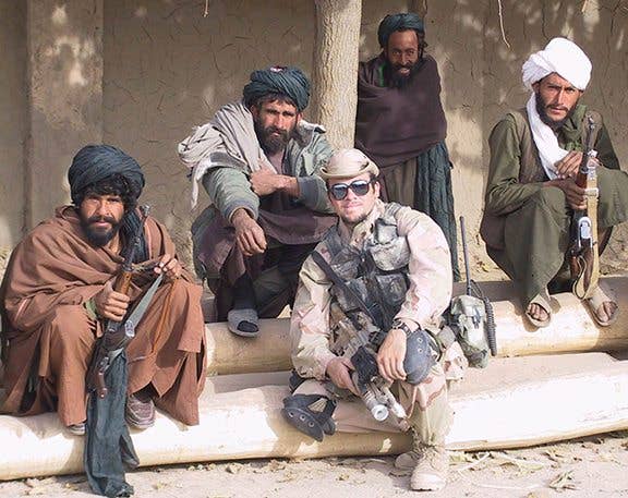 Now-Chief Warrant Officer 2 Brad Fowers poses with Afghan fighters and warlords who opposed the Taliban. Fowers served on one of the first Special Forces detachments from the U.S. Army Special Operations Command's 5th Special Forces Group (Airborne) to arrive in Afghanistan following 9-11. Their mission was to destroy the Taliban regime and deny Al-Qaeda sanctuary in Afghanistan. They scouted bomb targets and teamed with local resistance groups. (Photo courtesy of Chief Warrant Officer 2 Brad Fowers)