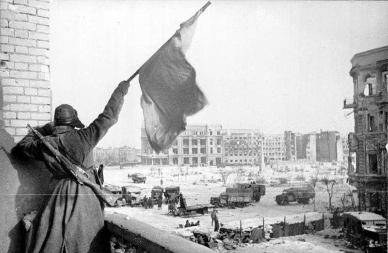 A Soviet soldier waving the Red Banner over the central plaza of Stalingrad in 1943. (Photo by Georgii Zelma)
