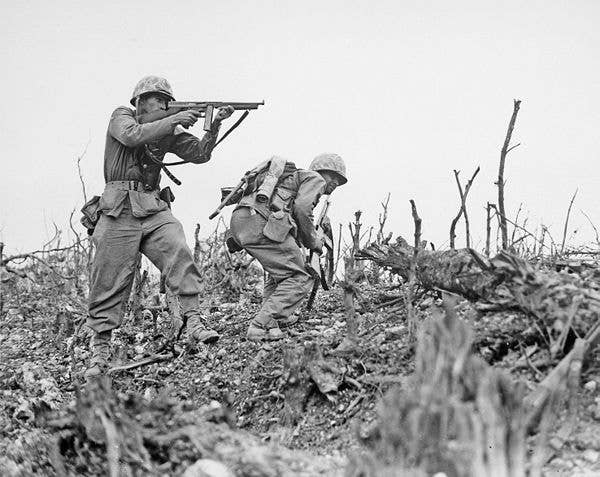 Two Marines from the 2nd Battalion, 1st Marine Regiment during fighting at Wana Ridge during the Battle of Okinawa, May 1945.Davis Hargraves provides covering fire with his M1 Thompson as Gabriel Chavarria, with a Browning Automatic Rifle, prepares to break cover to move to a different position.