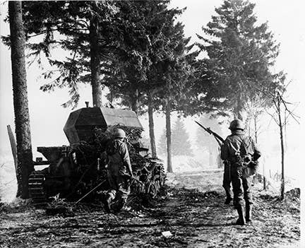 Infantry supporting engineers pass a knocked out German tank on their way to the front at Compogne, Belgium on Jan. 15, 1945. Photo: US Army