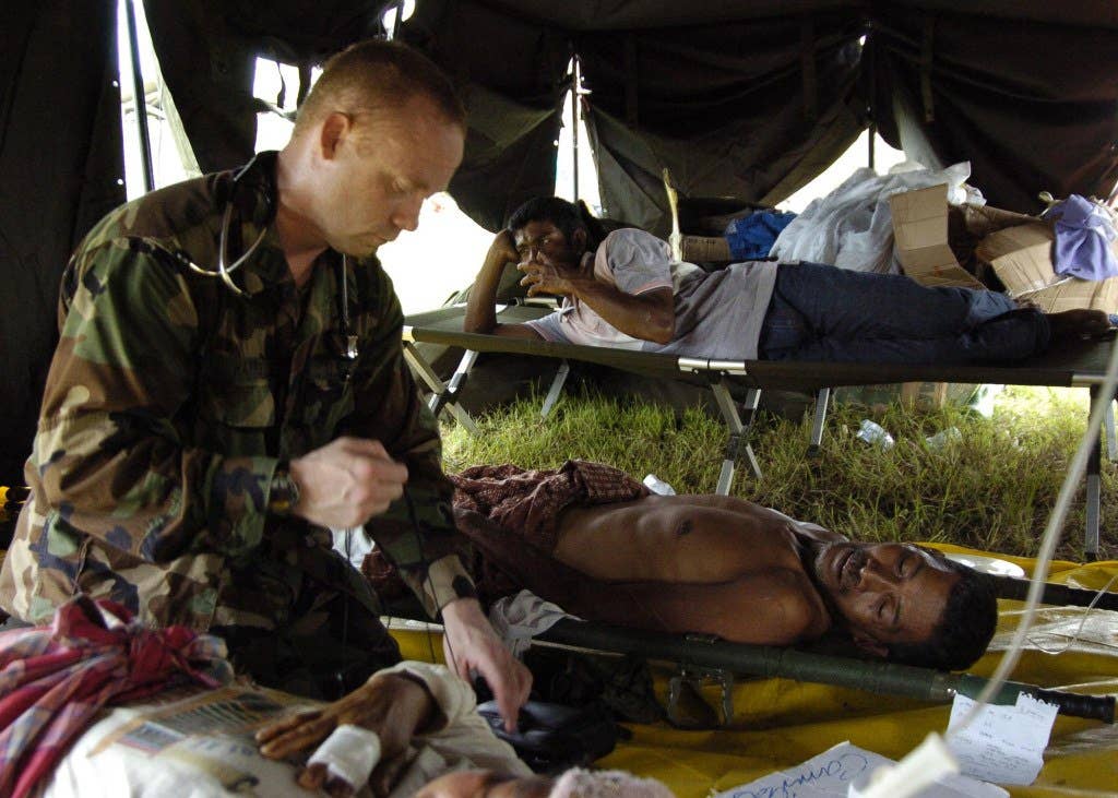A U.S. Navy doctor treats patients from tsunami-devastated villages in Banda Aceh, Sumatra, Indonesia, on Jan. 6, 2005. Helicopters from the USS Abraham Lincoln Carrier Strike Group are providing humanitarian assistance to areas devastated by the Dec. 26, 2004, Indian Ocean tsunami. The strike group is operating in the Indian Ocean off the coasts of Indonesia and Thailand in support of Operation Unified Assistance. DoD photo by Petty Officer 3rd class Tyler J. Clements, U.S. Navy. (Released)