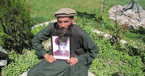 Khakimov poses with an old photo of himself in the Shindand area of Herat Province.