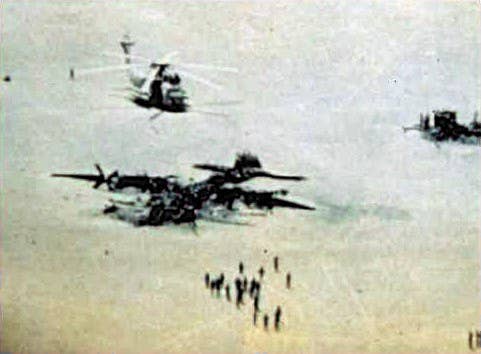 The burned out C-130 from the failed Operation Eagle Claw sits in the Iranian Desert. At far right is the destroyed helicopter. (Photo: US Special Operations Command)