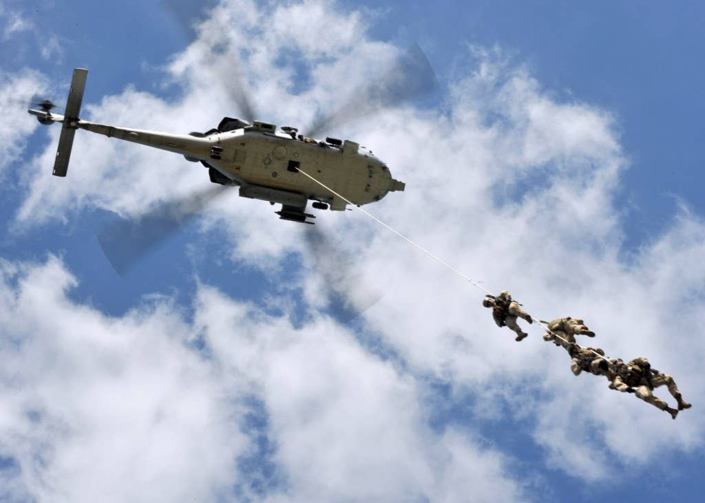 Navy SEALs demonstrate a special patrol insertion/extraction from an MH-60S Sea Hawk helicopter during a capabilities demonstration as part of the 2009 Veterans Day Ceremony and Muster XXIV at the National Navy UDT-SEAL Museum in Fort Pierce, Fla. The annual muster is held at the museum, which is located on the original training grounds of the Scouts and Raiders.