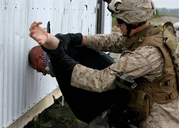 A Marine subdues a role player while practicing search procedures.