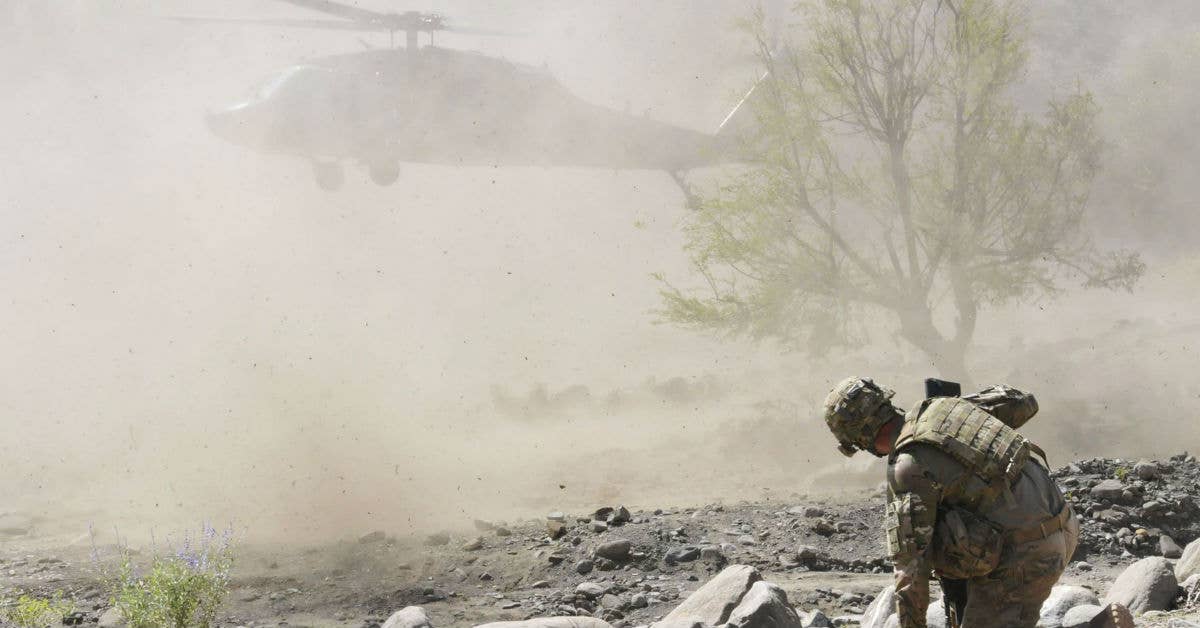 A member of Company B, Task Force 2-28, 172nd Infantry Brigade, braces against the prop wash from a UH-60 Black Hawk while securing the landing zone in a stream bed by the small village of Derka near Combat Outpost Zerok, Sept. 20, 2011. DoD Photo by Spc. Ken Scar