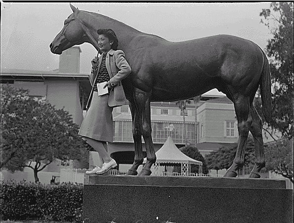 Lily Okuru, an internee, poses with the Seabiscuit statue at Santa Anita Recetrack in 1942 (US government photo)