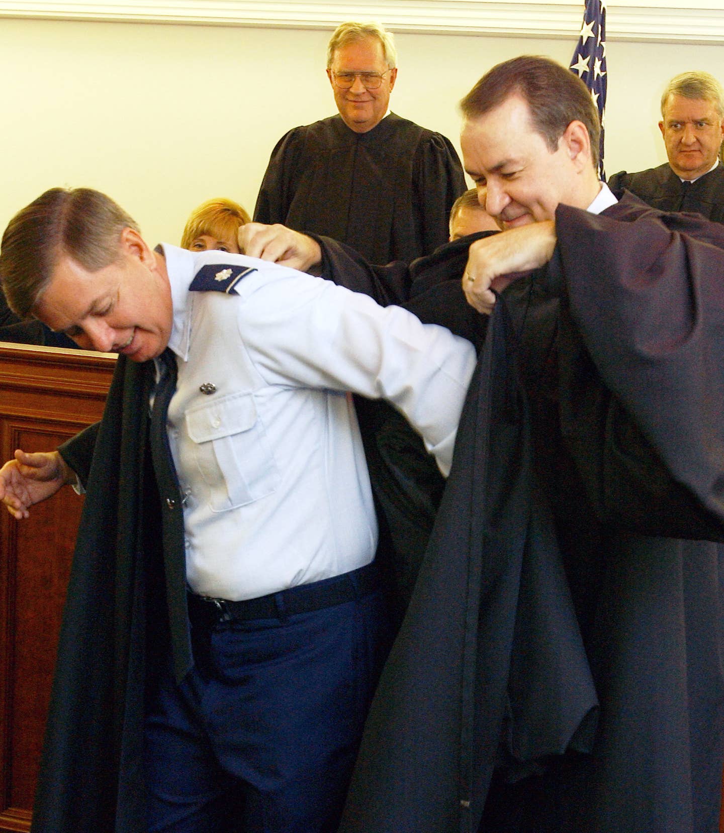 Col. James Van Orsdol (right) helps Lt. Col. Lindsey Graham don a judge's robe in a courtroom after Graham was sworn in as a new judge for the Air Force Court of Criminal Appeals. (U.S. Air Force photo by Staff Sgt. Amber K. Whittington)